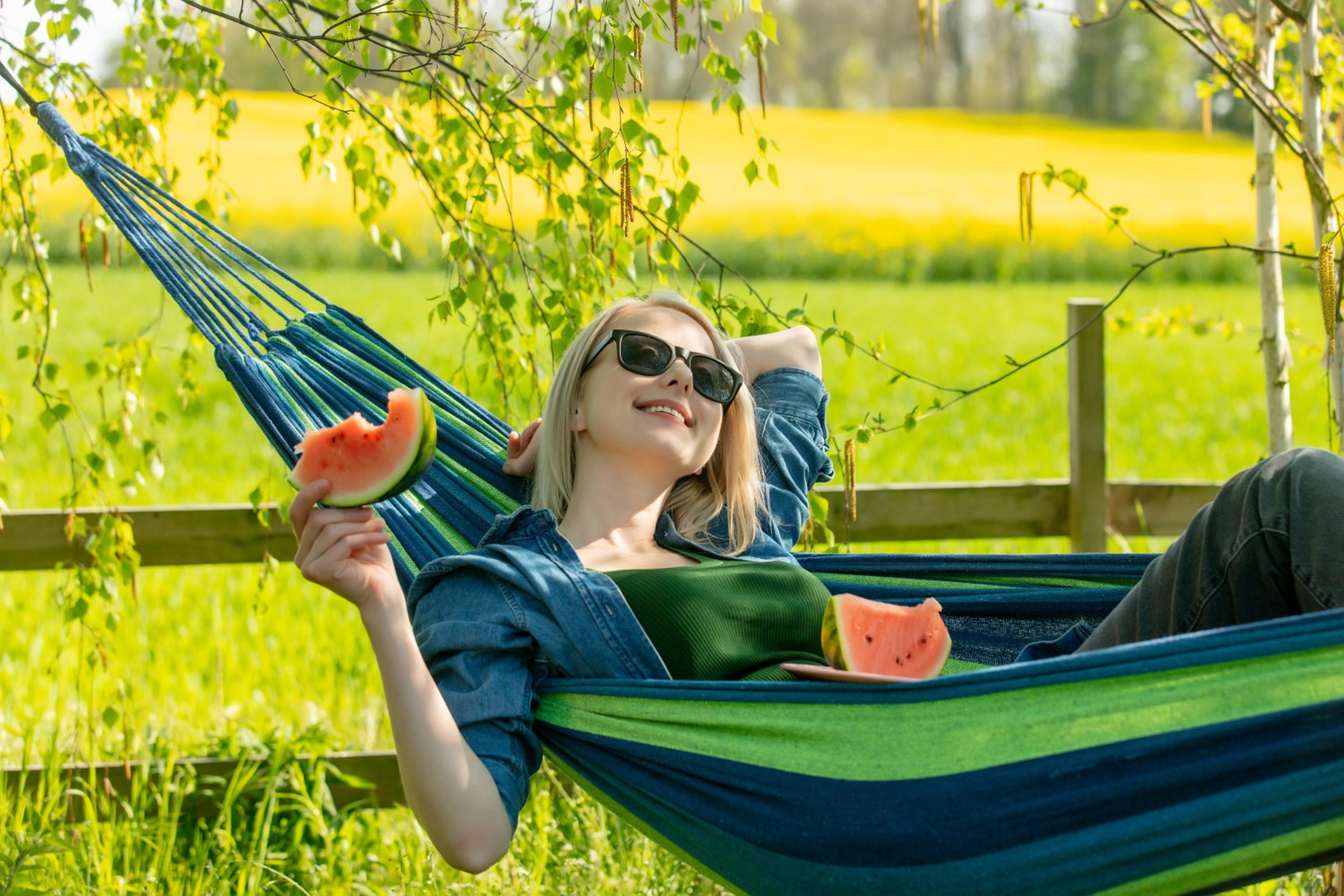 A woman eating watermelon in a hammock